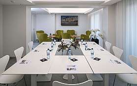 Bright meeting room with green chairs and water bottles on tables.